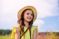 A smiling cute girl, in a straw hat , stands in nature in the summer, against the background of a blue sky, looks away Royalty Free Stock Photo