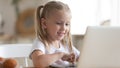 Smiling little girl using laptop close up, looking at screen Royalty Free Stock Photo