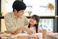 Smiling and cute young Asian girl having a great time with her dad, painting watercolor together Royalty Free Stock Photo