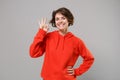 Smiling cute young brunette woman girl in casual red hoodie posing isolated on grey wall background studio portrait Royalty Free Stock Photo