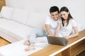 Smiling and cute young couple is sitting white sofa and uses laptop Royalty Free Stock Photo