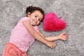 Young girl with plush red heart lying on the carpet Royalty Free Stock Photo