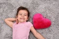 Young girl with plush red heart lying on the carpet Royalty Free Stock Photo