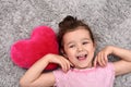 Young girl with plush red heart lying on the carpet Royalty Free Stock Photo