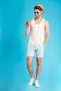 Smiling cute young man standing and using mobile phone Royalty Free Stock Photo