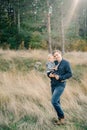 Smiling dad with a little daughter in his arms stands in dry grass at the edge of the forest Royalty Free Stock Photo