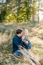 Smiling dad with a little girl on his knees sit on the lawn in the park Royalty Free Stock Photo