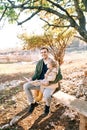 Smiling dad with a little girl on his lap sitting on a bench with a colorful book in his hands