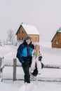 Smiling dad with a little girl on his lap sitting on a snow-covered fence in the village Royalty Free Stock Photo