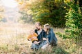 Smiling dad and mom sit on the grass in the park with their little son in their arms and look at him Royalty Free Stock Photo