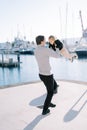 Smiling dad spins a little girl in his arms on the pier. Back view Royalty Free Stock Photo