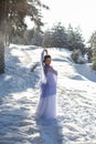 Vertical portrait against the background of the winter landscape of a cute brunette in a long white dress and a light purple Royalty Free Stock Photo