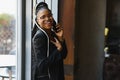 Smiling dark skinned woman in trendy wear laving cafe talking on mobile phone via roaming tariffs,african american millennial Royalty Free Stock Photo