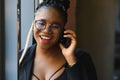 Smiling dark skinned woman in trendy wear laving cafe talking on mobile phone via roaming tariffs,african american millennial Royalty Free Stock Photo