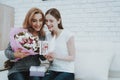 Smiling Daughter Gives Mother Flowers and Gift