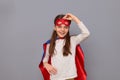 Smiling delighted cheerful joyful little girl wearing superhero costume and mask isolated over gray background looking at camera Royalty Free Stock Photo