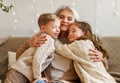 Loving senior grandmother hugging cute happy grandchildren during winter holidays at home