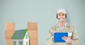 Smiling delivery man holding clipboard by house and parcels Royalty Free Stock Photo