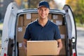 Smiling delivery man standing in front of his van holding a package Royalty Free Stock Photo