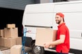 smiling delivery man in uniform with cardboard box standing near white van Royalty Free Stock Photo