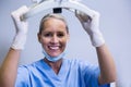 Smiling dental assistant adjusting light in clinic