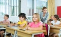 Smiling diligent preteen girl studying with classmates in school