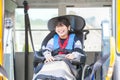 Smiling disabled boy in wheelchair on yellow school bus lift Royalty Free Stock Photo