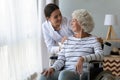 Smiling disabled elderly woman in wheelchair talking with caring nurse