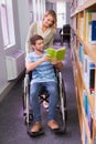 Smiling disabled student with classmate in library Royalty Free Stock Photo