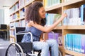 Smiling disabled student in library picking book Royalty Free Stock Photo