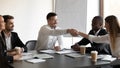 Smiling diverse business partners handshake greeting at meeting