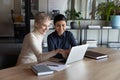 Smiling diverse colleagues using laptop together, chatting, discussing project Royalty Free Stock Photo