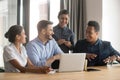 Smiling diverse employees talk brainstorming in office using laptop Royalty Free Stock Photo