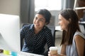 Smiling diverse female interns talking in office discussing onli