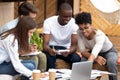 Smiling diverse friends doing paperwork together in cafe