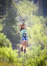 Smiling diverse girl riding a zipline through the forest Royalty Free Stock Photo