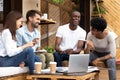 Smiling diverse millennial friends have fun studying in cafe