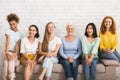 Smiling Diverse Women Sitting On Sofa Over White Brick Wall