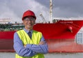 Smiling Dock and Vessel Supervisor in Red Hardhat Standing in front of Large Oil Tanker Royalty Free Stock Photo