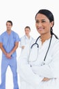Smiling doctor with arms folded and colleagues behind her Royalty Free Stock Photo