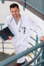 smiling doctor carries folder as he walks up stairs Royalty Free Stock Photo