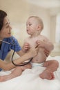 Smiling doctor checking a baby's heart beat with a stethoscope in the doctors office Royalty Free Stock Photo