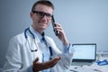 Smiling doctor having phone call at desk. Physicianr talking with his patient in office clinic sitting at table with Royalty Free Stock Photo