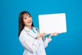 Smiling doctor holding blank banner or card with stethoscope on blue background Royalty Free Stock Photo