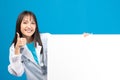 Smiling doctor holding blank banner or card with stethoscope on blue background Royalty Free Stock Photo