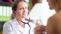 Smiling doctor listening heart or lungs of male patient with stethoscope
