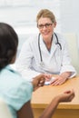 Smiling doctor listening to her patient and taking notes