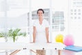 Smiling doctor looking at camera standing behind massage table