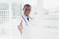 Smiling doctor offering a handshake in a medical office