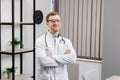 Smiling doctor posing with arms crossed in the office. Man is wearing a stethoscope and glasses. Medical staff on the workplace Royalty Free Stock Photo